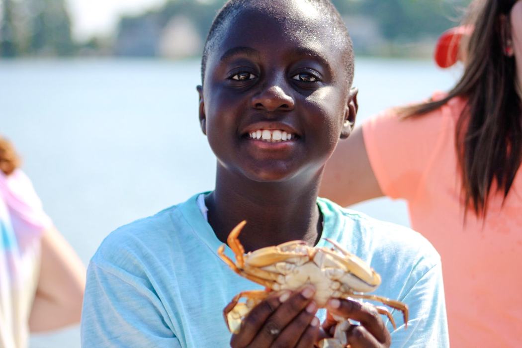Child holding a crab by the waterfront
