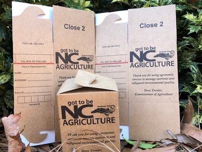 Brown cardboard agriculture sample boxes labeled "Close 2" and "got to be NC AGRICULTURE"