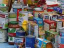 Assorted canned goods, boxed pasta mixes, jars, and condiments arranged on a table