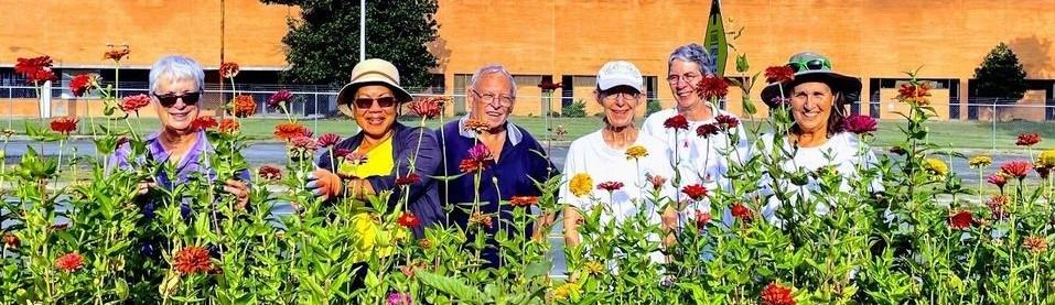 Master Gardener volunteers standing in front of bed of zinnias