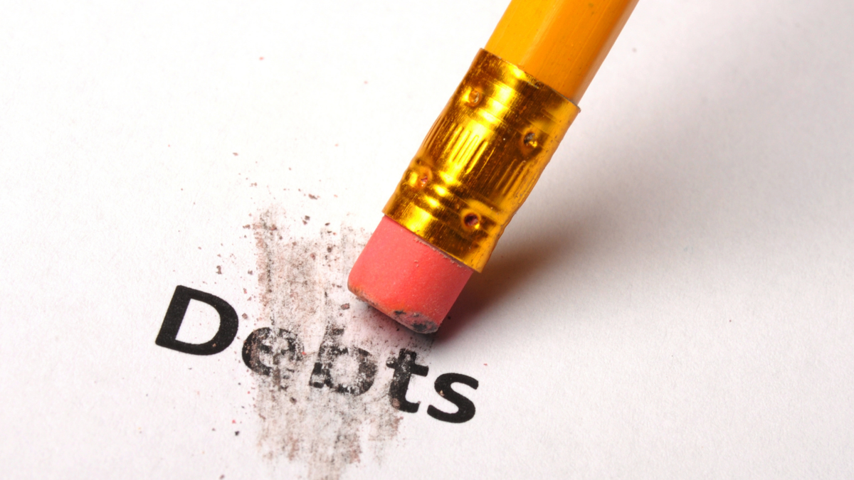 Pencil eraser rubbing the word "Debts", smudging letters and leaving eraser shavings