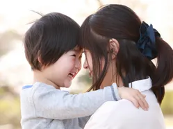 Young child and adult woman touching foreheads while embracing