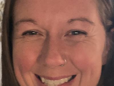 Close-up of smiling adult woman with long hair and a small nose ring