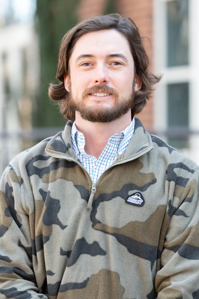 Bearded man wearing camo Hurley fleece and checked shirt, standing outdoors
