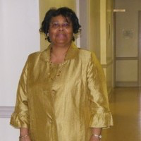 Woman standing in a hallway wearing a gold jacket and blouse