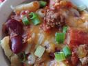 Baked potato topped with chili, kidney beans, melted cheese, and chopped green onions