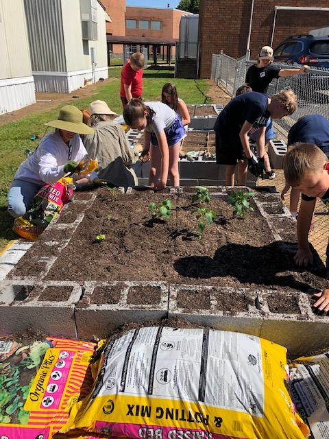 Two adults and 8 children working in 2 raised beds. 