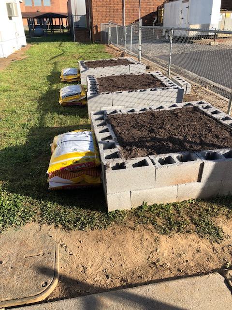 Three concrete raised beds filled with dirt