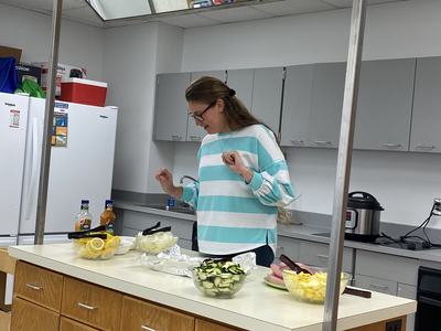 Woman in striped shirt preparing bowls of sliced vegetables on a kitchen counter