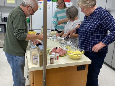 Four people preparing and arranging food on a kitchen island counter.