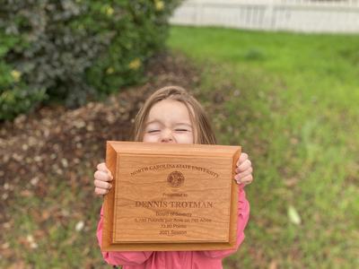 Child holding a plaque received by Dennis Trotman