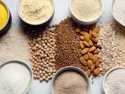 Assorted grains, flours, oats, almonds and chickpeas in bowls and piles