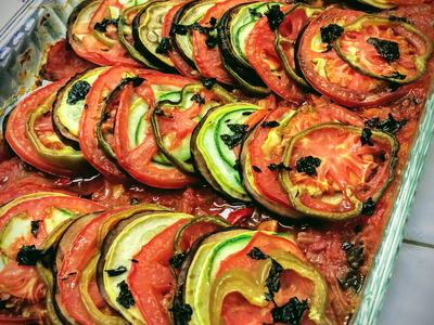baked ratatouille. Layers of eggplant, tomatoes, peppers with basil sprinkled over.