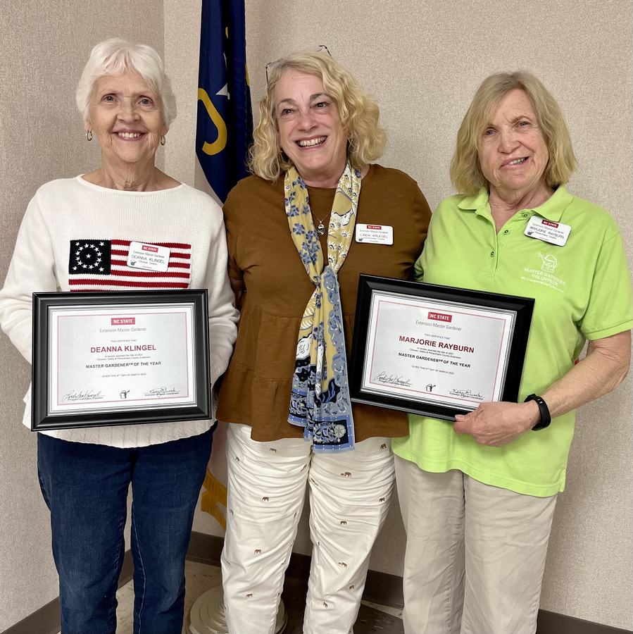 Three women standing; two hold framed certificates: "Deanna Klingel" and "Marjorie Rayburn, Master Gardener of the Year."