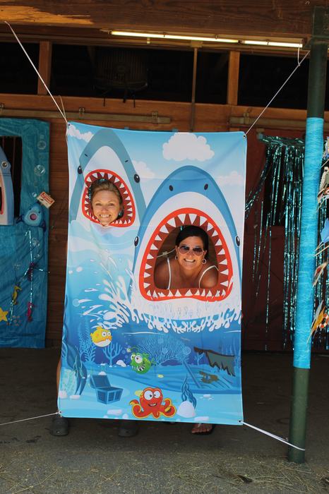 Two faces through shark-mouth cutouts on an ocean-themed banner.