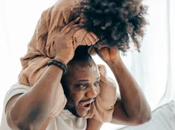 Man carrying child on his shoulders indoors, child seated facing forward