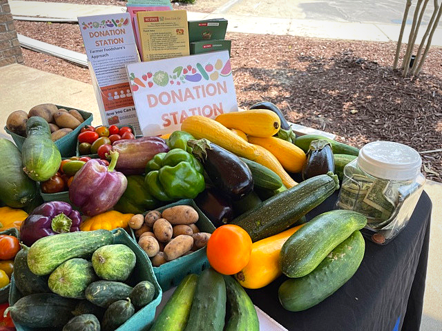 Table of fresh vegetables and tip jar beside a sign reading "DONATION STATION"
