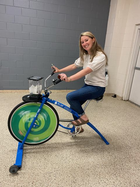 Person pedaling a stationary blender bike with a blender mounted on the front wheel