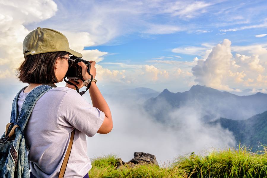 teen hiker takes a photo of a foggy mountain landscape