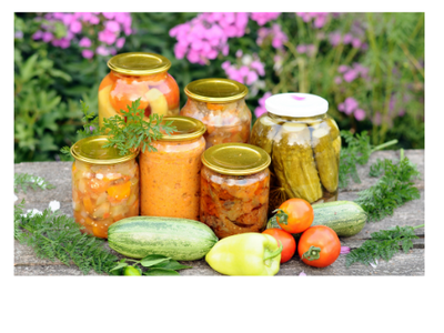 Assorted sealed glass jars of pickled vegetables and preserves with fresh produce