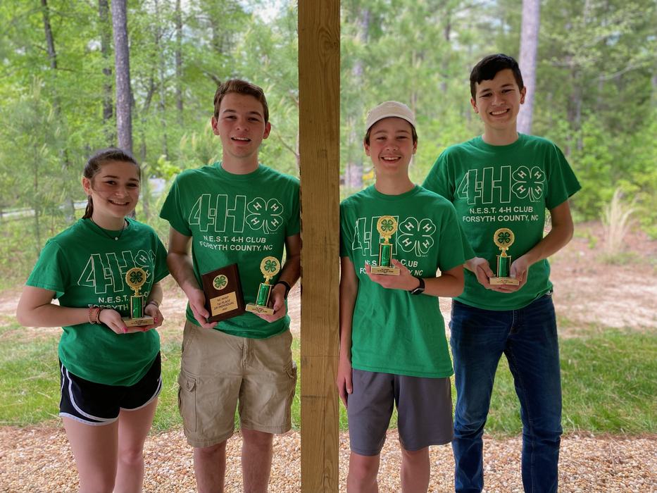 Four 4-H youth wearing green shirts, holding their 1st place trophies. 
