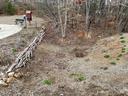 Dry landscaped drainage swale with metal grate, log border, small red book box and bench