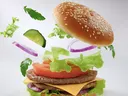 A cheeseburger with ingredients exploding upwards from the base. 