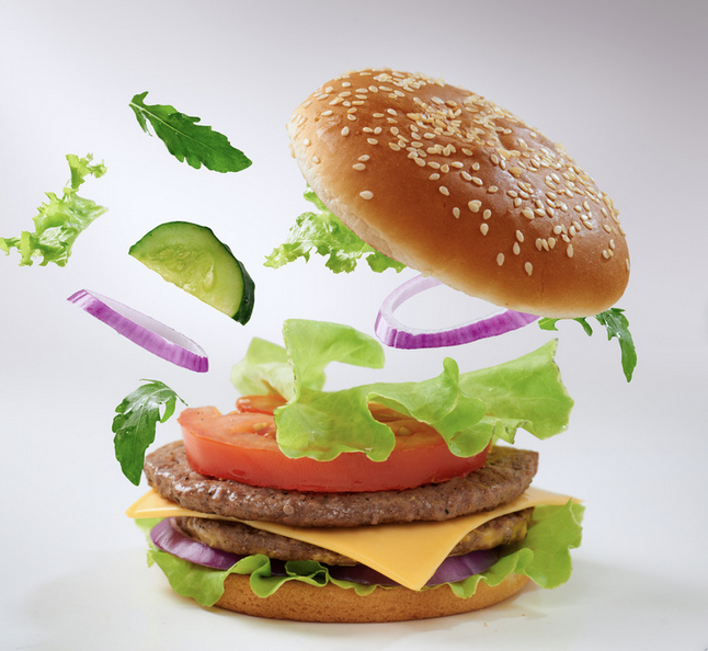 A cheeseburger with ingredients exploding upwards from the base. 