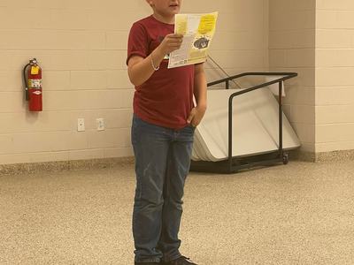 Child standing in a room reading a yellow pamphlet