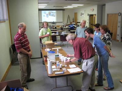 Photo of several people gathered around a table watching a demonstration