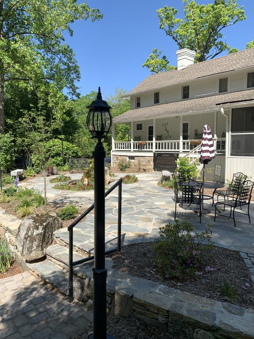 A black lamp post sits in front of a staircase leading up to a house. 