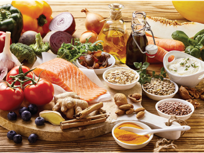 Assorted healthy foods on wooden board: salmon, tomatoes, vegetables, nuts, seeds, oils