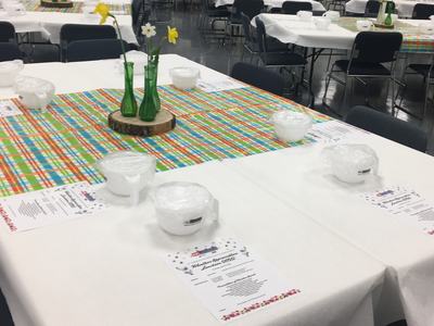 Tables set for Volunteer Appreciation Luncheon with covered bowls, menus, and daffodil centerpieces