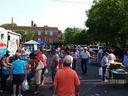 Outdoor market in a parking lot with people browsing vendor stalls and trucks