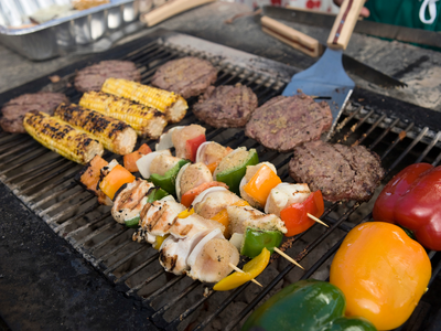 Grill with chicken and vegetable skewers, burger patties, grilled corn and bell peppers