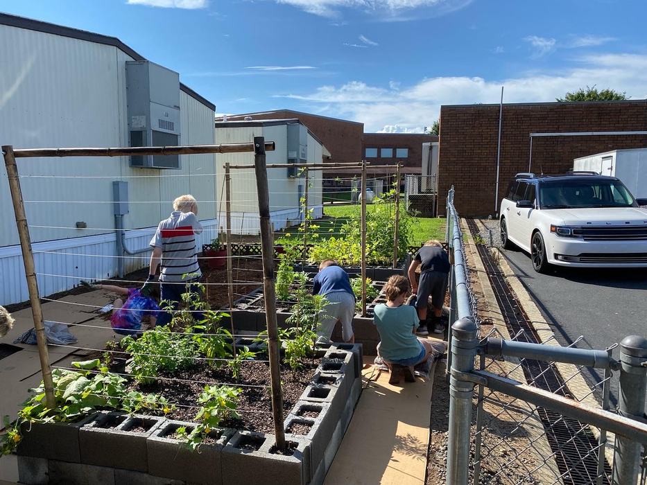 Children work in a raised garden bed.