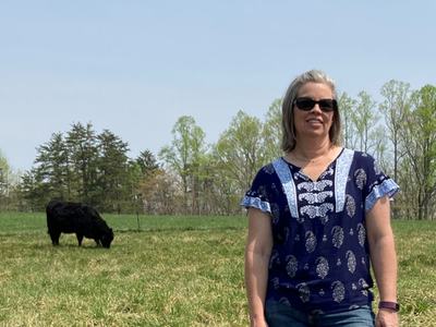 April Bowman in a pasture with a black cow.