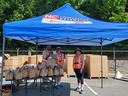 Volunteers in orange vests distributing brown paper bags under NC Cooperative Extension tent