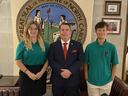 Three people standing before the Great Seal of the State of North Carolina (May 20, 1775)