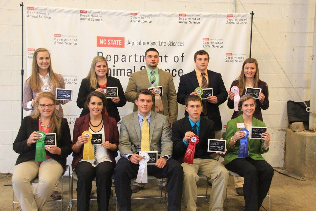Teenagers display their awards while standing in from of the Department of Animal Science Banner.