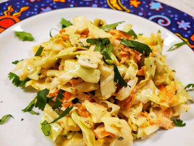 Plate of creamy cabbage and carrot salad garnished with parsley