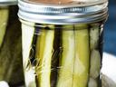 Ball mason jar of vertical pickle spears in brine with dill sprig