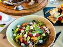 Bowl of Greek salad with feta, olives, tomatoes, and cucumber on a table