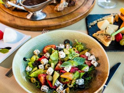 Bowl of Greek salad with feta, olives, tomatoes, and cucumber on a table