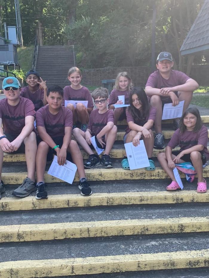 A group of students wearing matching outfits sit together on concrete steps.