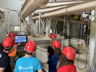 Group of people in red hard hats watching a control monitor inside an industrial plant