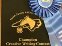 North Carolina 4‑H Champion Creative Writing Contest folder with blue ribbon labeled JUNIOR