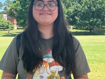 A teenager gives the camera two thumbs up.