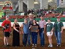 Group of eight people in an indoor arena holding a framed award; logo reads "NC State 4-H Horse Show"