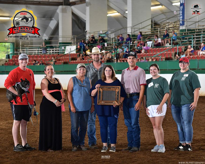 Group of eight people in an indoor arena holding a framed award; logo reads "NC State 4-H Horse Show"